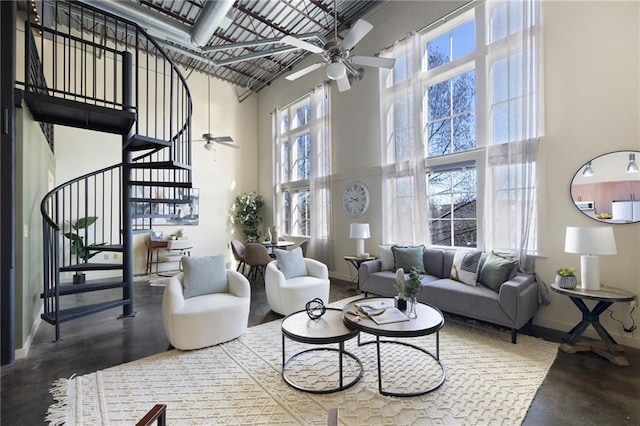 living area with baseboards, stairs, a high ceiling, and ceiling fan