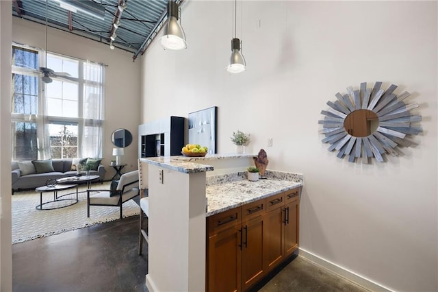 kitchen featuring a peninsula, finished concrete floors, a high ceiling, and a breakfast bar