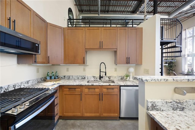 kitchen with stainless steel appliances, concrete flooring, a sink, and light stone countertops