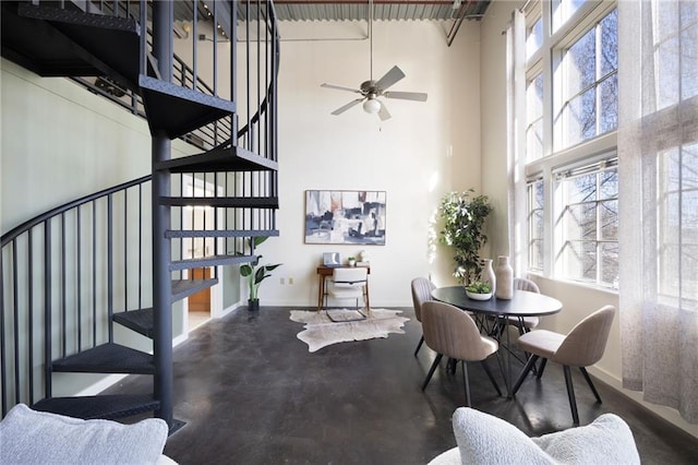 dining space featuring a healthy amount of sunlight, a towering ceiling, baseboards, and stairs