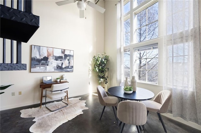 dining area with baseboards, finished concrete flooring, and a high ceiling