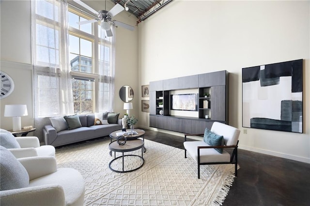 living room with a ceiling fan, a wealth of natural light, baseboards, and a high ceiling