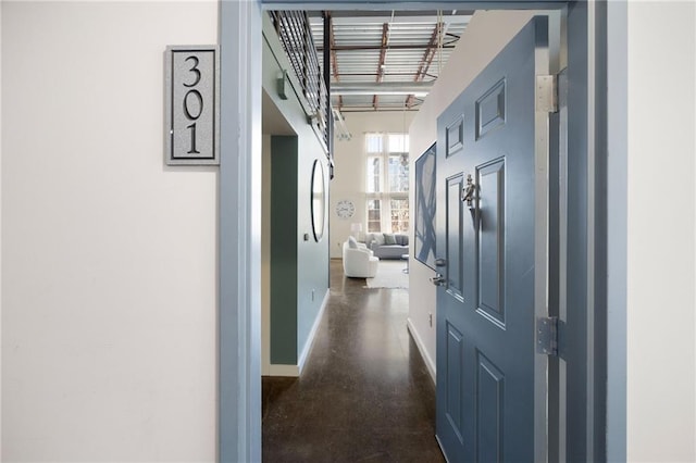 corridor featuring concrete flooring and baseboards