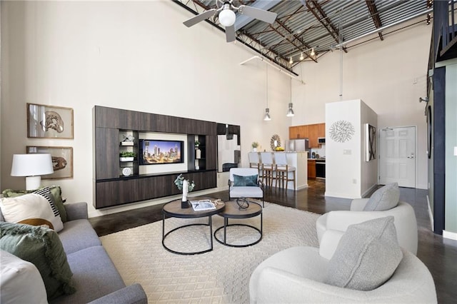 living room featuring baseboards, a fireplace, ceiling fan, and a high ceiling