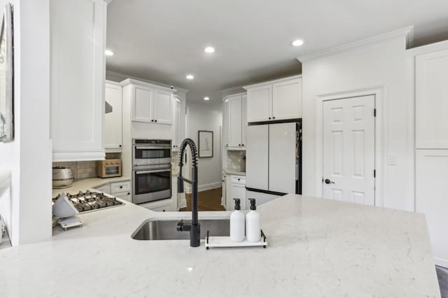 4944 Dovecote Trl, Suwanee, GA 30024 - kitchen with appliances with stainless steel finishes, recessed lighting, white cabinetry, light stone counters, and tasteful backsplash