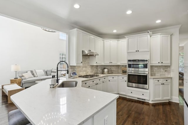 4944 Dovecote Trl, Suwanee, GA 30024 - kitchen featuring stainless steel double oven, under cabinet range hood, white cabinetry, light stone counters, and decorative backsplash