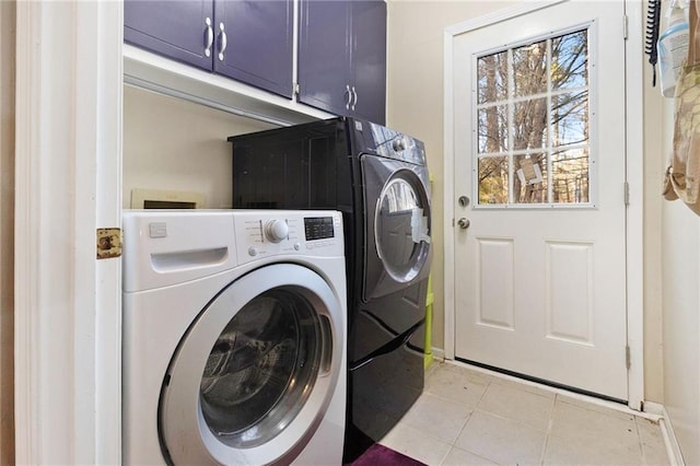 laundry area featuring cabinet space, washing machine and clothes dryer, and light tile patterned floors