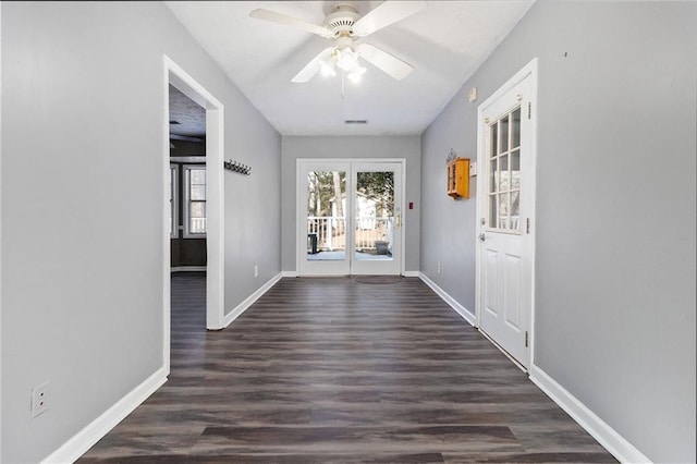 doorway with ceiling fan, dark wood-type flooring, and baseboards