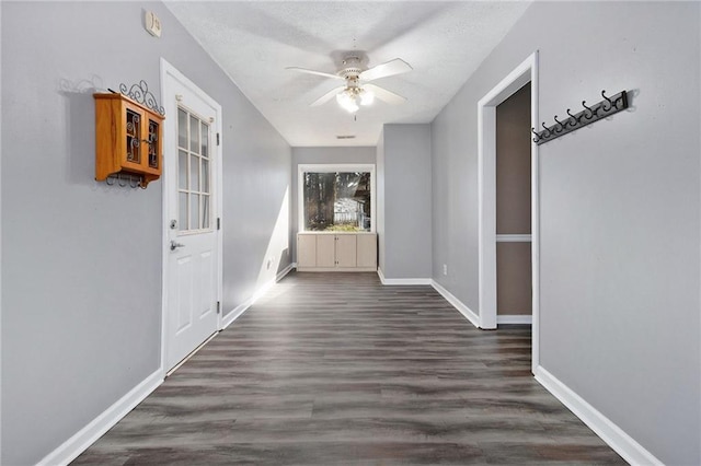 hallway featuring a textured ceiling, baseboards, and wood finished floors