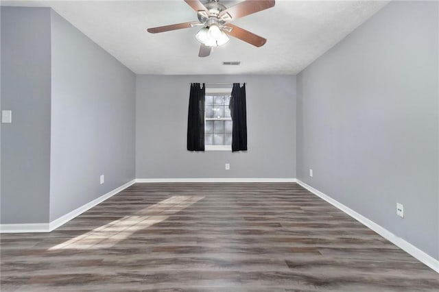 spare room featuring visible vents, baseboards, ceiling fan, and wood finished floors