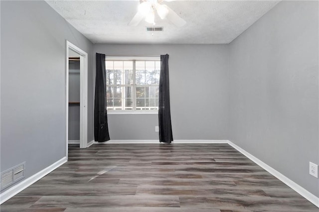 spare room featuring baseboards, visible vents, and wood finished floors