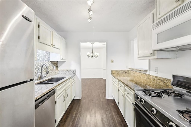 kitchen with light stone counters, decorative light fixtures, white cabinets, appliances with stainless steel finishes, and sink