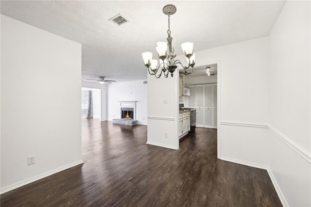 interior space with ceiling fan with notable chandelier, dark hardwood / wood-style flooring, and a textured ceiling