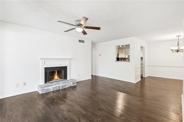 unfurnished living room with ceiling fan with notable chandelier, a textured ceiling, and dark wood-type flooring