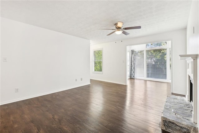 unfurnished living room with ceiling fan, dark hardwood / wood-style floors, a textured ceiling, and a fireplace