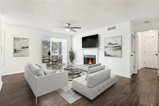 living room featuring a textured ceiling, ceiling fan, and dark wood-type flooring