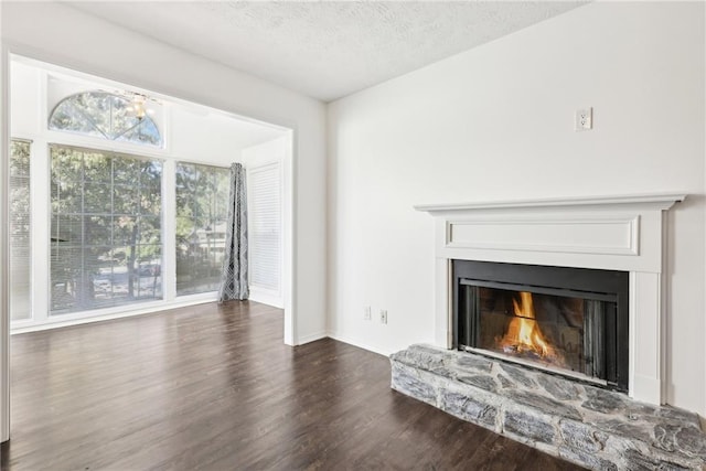 unfurnished living room with a textured ceiling, dark hardwood / wood-style floors, and plenty of natural light