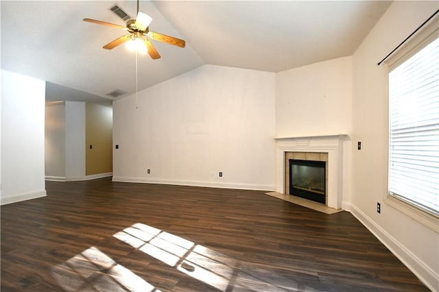 unfurnished living room featuring ceiling fan, dark hardwood / wood-style flooring, a tile fireplace, and vaulted ceiling