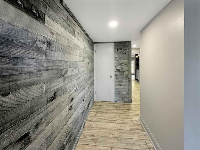 hallway with wooden walls and light hardwood / wood-style floors