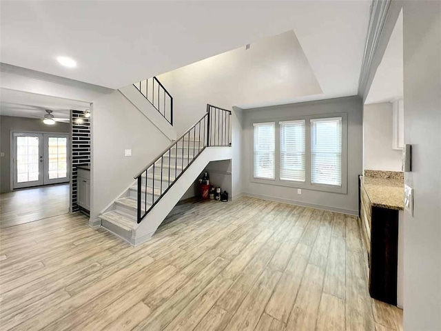 unfurnished living room featuring ceiling fan, french doors, and light hardwood / wood-style floors