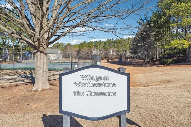 view of property's community featuring a tennis court and fence