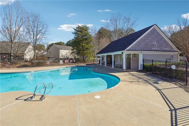 community pool with an outbuilding, a patio, an exterior structure, and fence