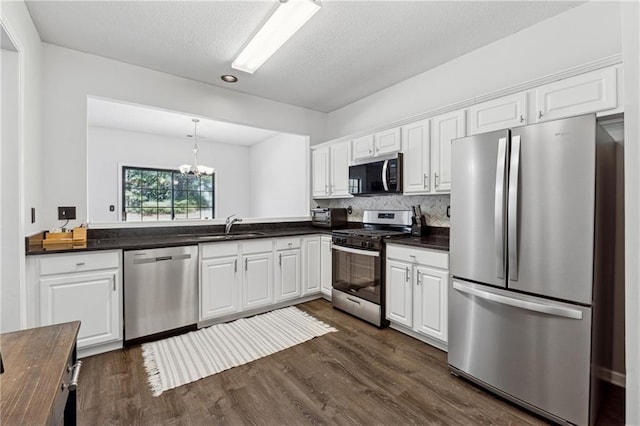 kitchen with stainless steel appliances, a sink, white cabinets, decorative backsplash, and dark wood-style floors