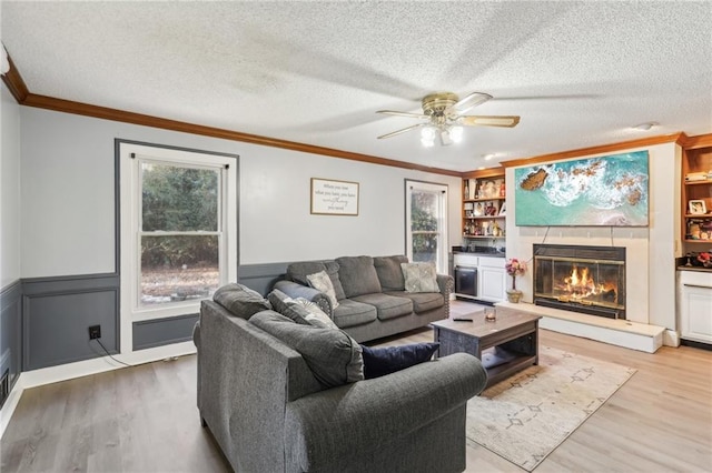 living room with crown molding, light wood-type flooring, built in features, and a textured ceiling