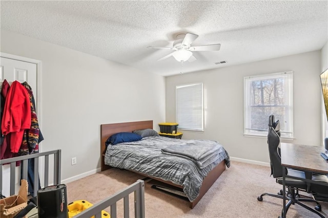 bedroom featuring ceiling fan, light carpet, and a textured ceiling