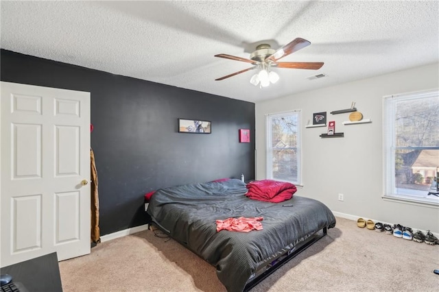 carpeted bedroom featuring ceiling fan and a textured ceiling