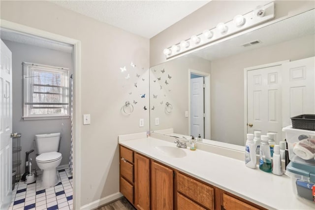 bathroom with vanity, toilet, and a textured ceiling