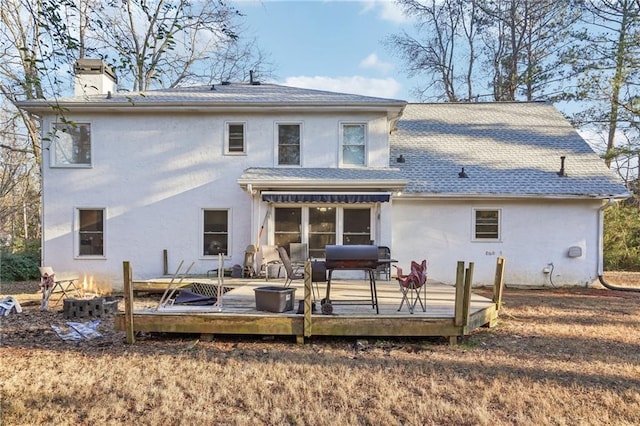 rear view of property with a wooden deck and an outdoor fire pit