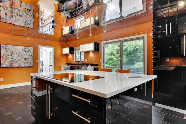 2683 Tritt Springs Trce NE, Marietta, GA 30062 - kitchen with black electric cooktop, dark cabinets, open floor plan, a center island with sink, and a towering ceiling