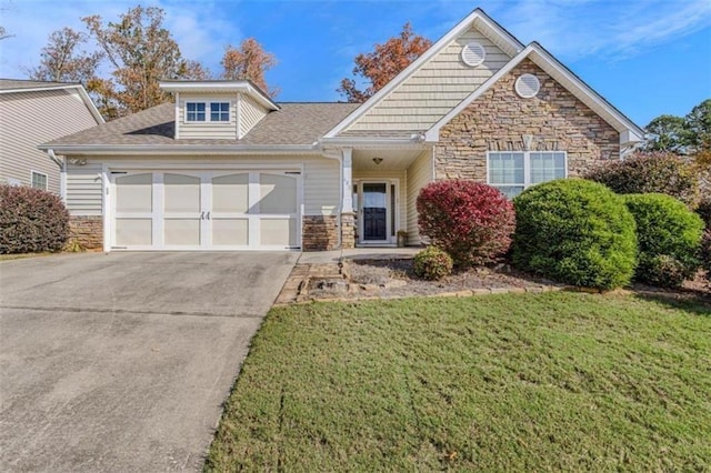 view of front of home featuring a front yard, stone siding, driveway, and an attached garage