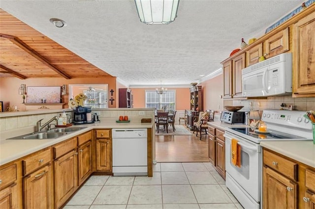 kitchen featuring light tile patterned floors, white appliances, a sink, tasteful backsplash, and brown cabinetry