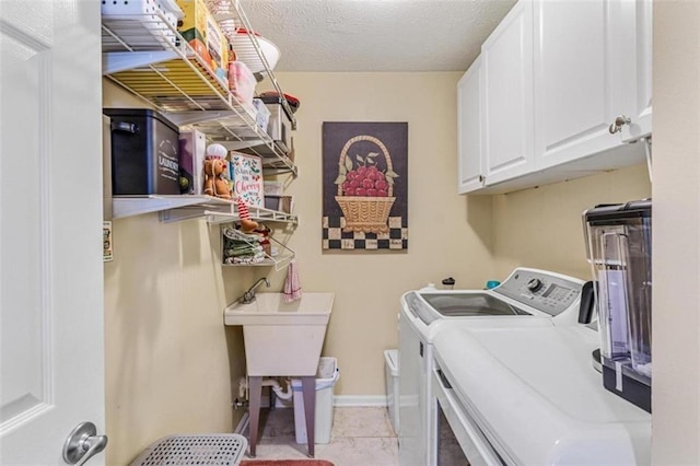 laundry room with light tile patterned floors, a textured ceiling, separate washer and dryer, baseboards, and cabinet space