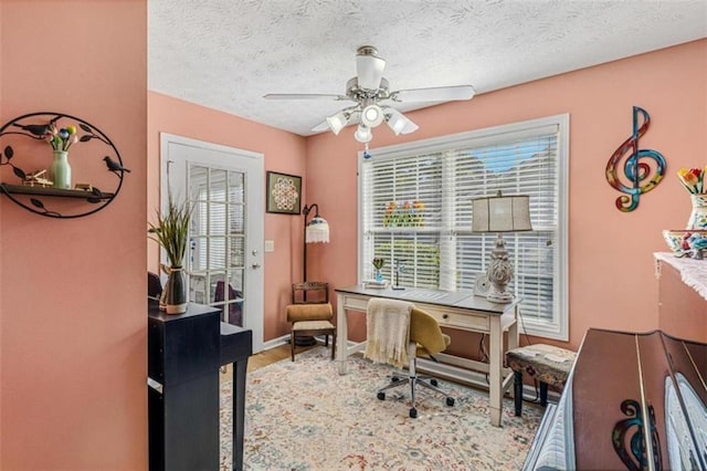 office featuring ceiling fan, a textured ceiling, baseboards, and wood finished floors