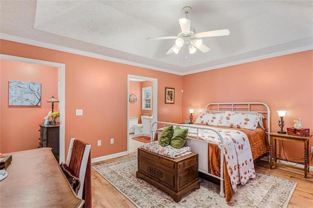 bedroom with baseboards, a raised ceiling, ornamental molding, wood finished floors, and a textured ceiling