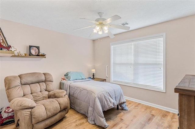 bedroom featuring ceiling fan, light wood-type flooring, visible vents, and baseboards