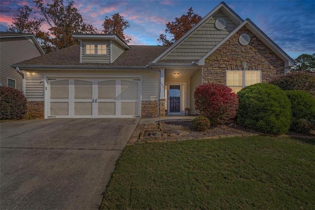 view of front of home with a garage, stone siding, and driveway