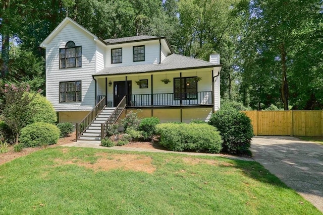 view of front of home with a front yard, fence, covered porch, a chimney, and stairs