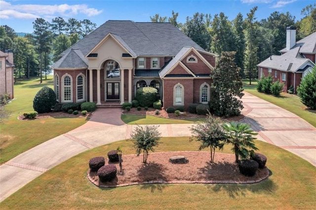 view of front of property featuring a front lawn, concrete driveway, and brick siding