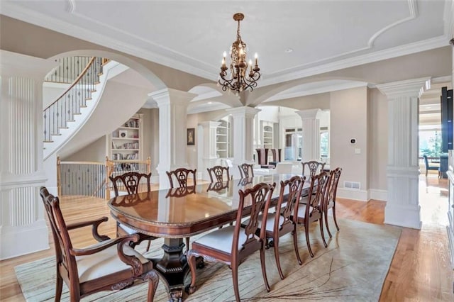 dining room with ornate columns, visible vents, light wood finished floors, and arched walkways