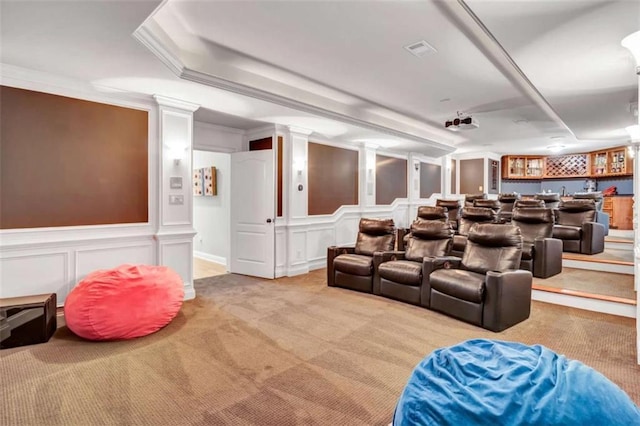 carpeted cinema featuring wainscoting, ornamental molding, wet bar, ornate columns, and a decorative wall