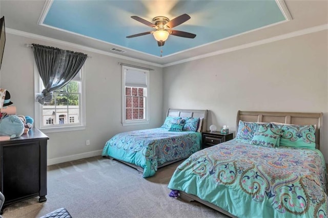 carpeted bedroom featuring baseboards, a tray ceiling, visible vents, and crown molding