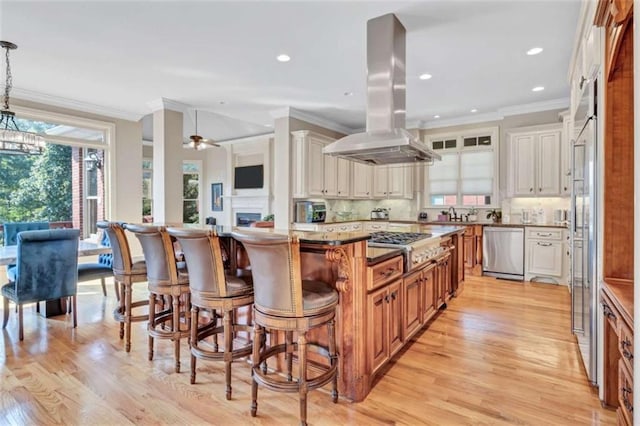 kitchen featuring appliances with stainless steel finishes, island exhaust hood, decorative backsplash, and ornamental molding