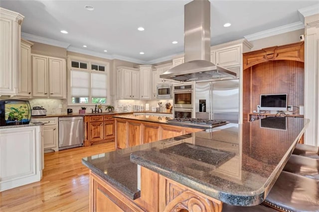 kitchen featuring built in appliances, island range hood, a large island, ornamental molding, and decorative backsplash