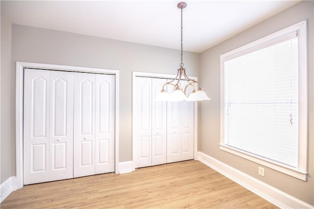 unfurnished dining area featuring light wood-type flooring and a chandelier