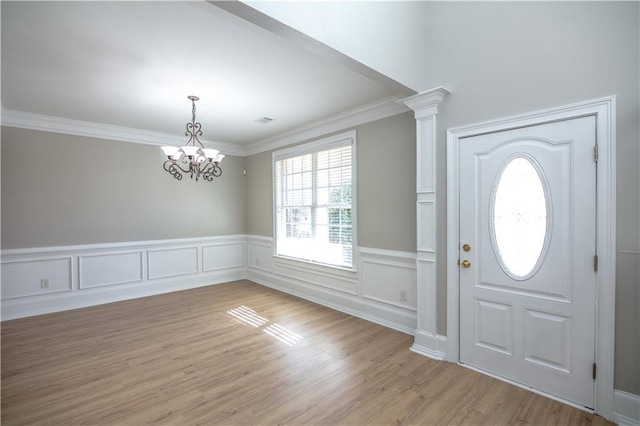 entryway with ornamental molding, a chandelier, light hardwood / wood-style flooring, and ornate columns