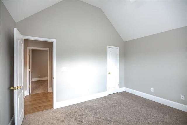 unfurnished bedroom featuring high vaulted ceiling and light carpet